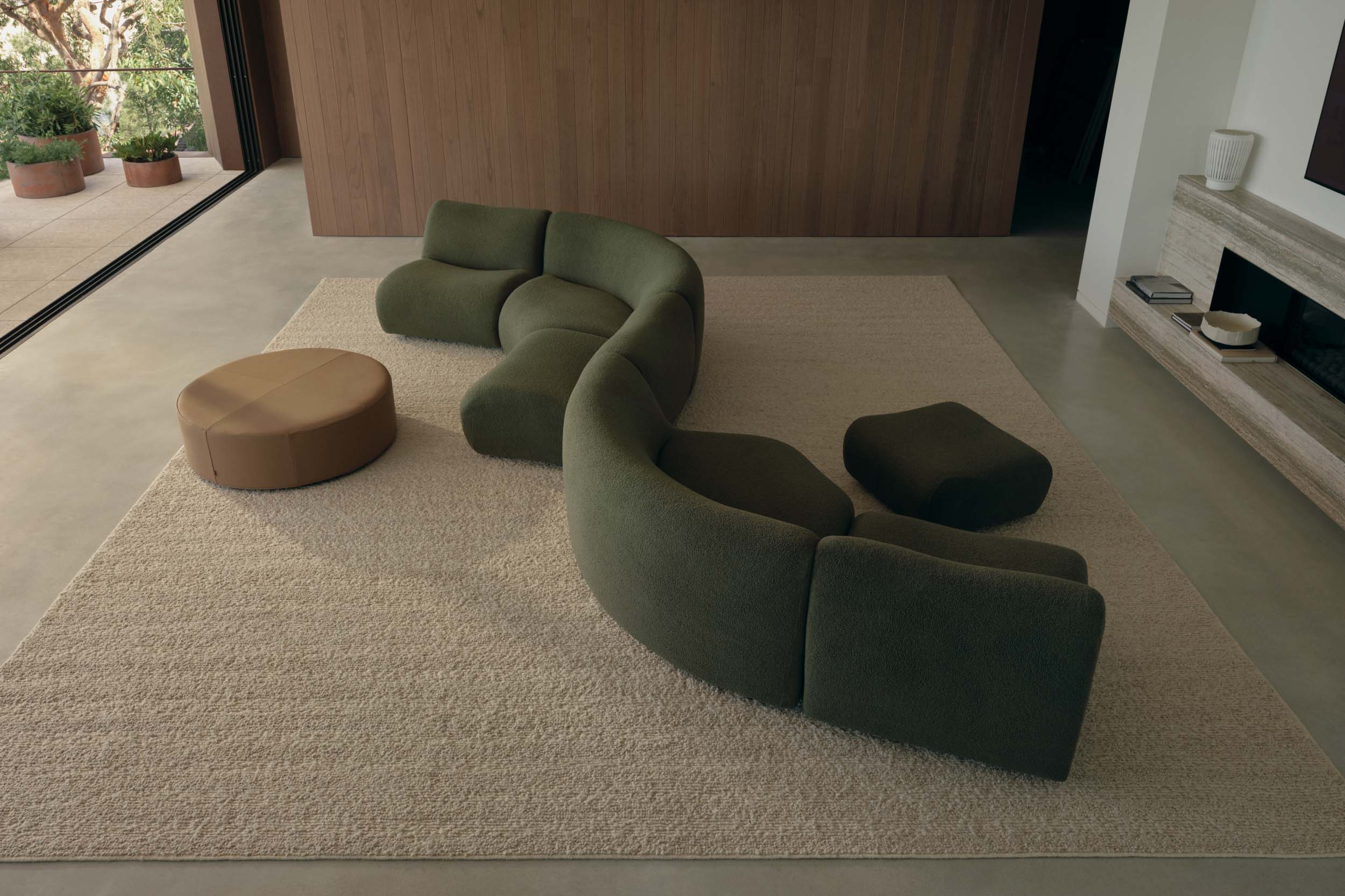 S-shape modular green sofa in a contemporary earthy living room.